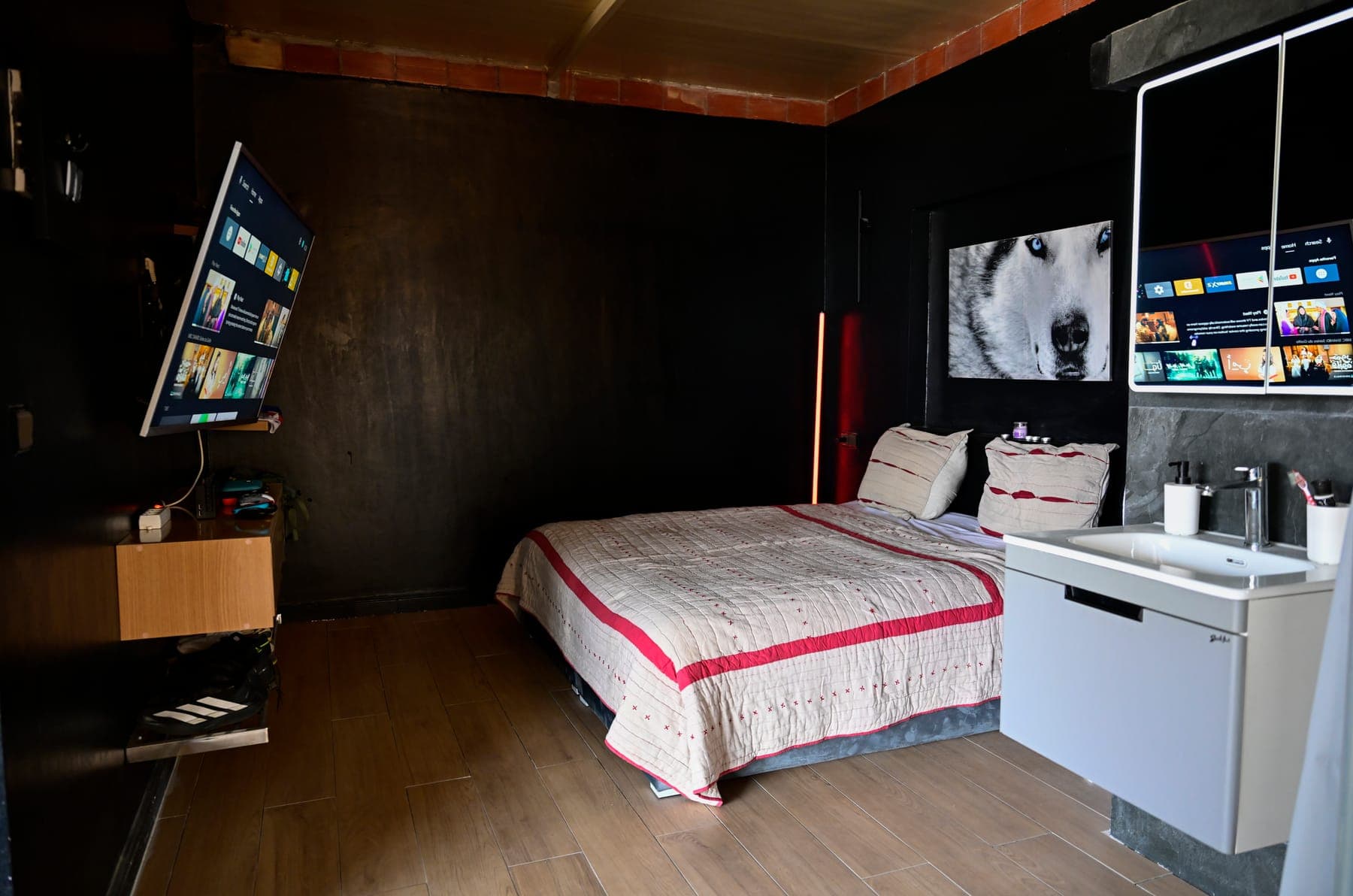 Vue d’ensemble de la chambre : écran, lit double, portrait de husky et vasque ouverte sur la pièce