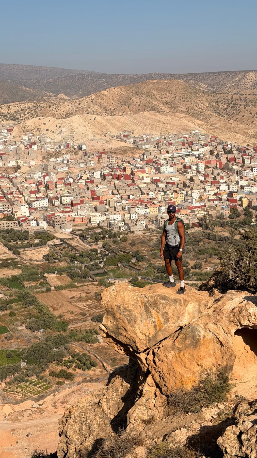 Hiker standing on a rocky outcrop above a Moroccan valley village