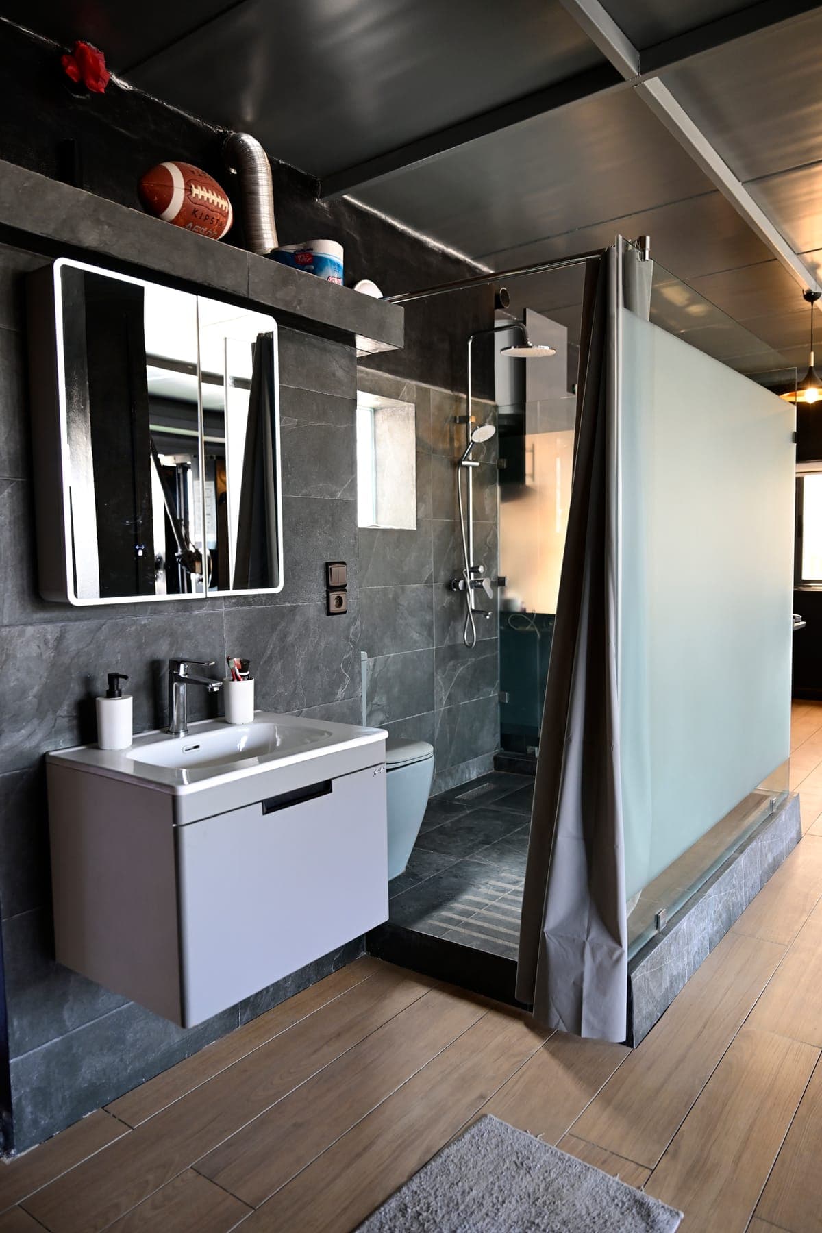 Salle de bain en pierre sombre : miroir LED, vasque suspendue et douche à l’italienne
