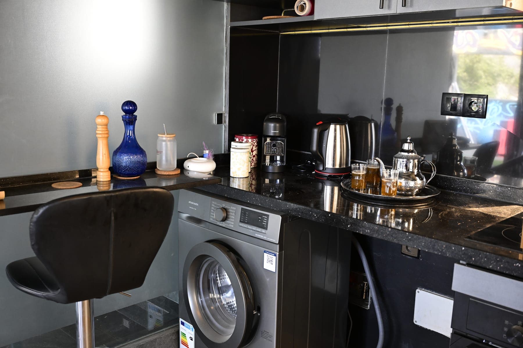 Plan de travail de la cuisine : bouilloire, théière marocaine, machine à café, plaques à induction et lave-linge